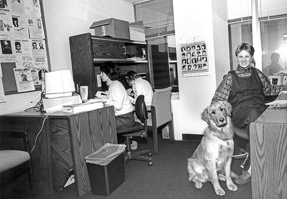 black and white photo of woman sitting at desk and golden retriever next to her