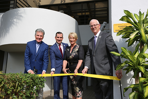 (l to r) john, callahan, and reve walsh next to john clark, cutting yellow ribbon in front of florida office