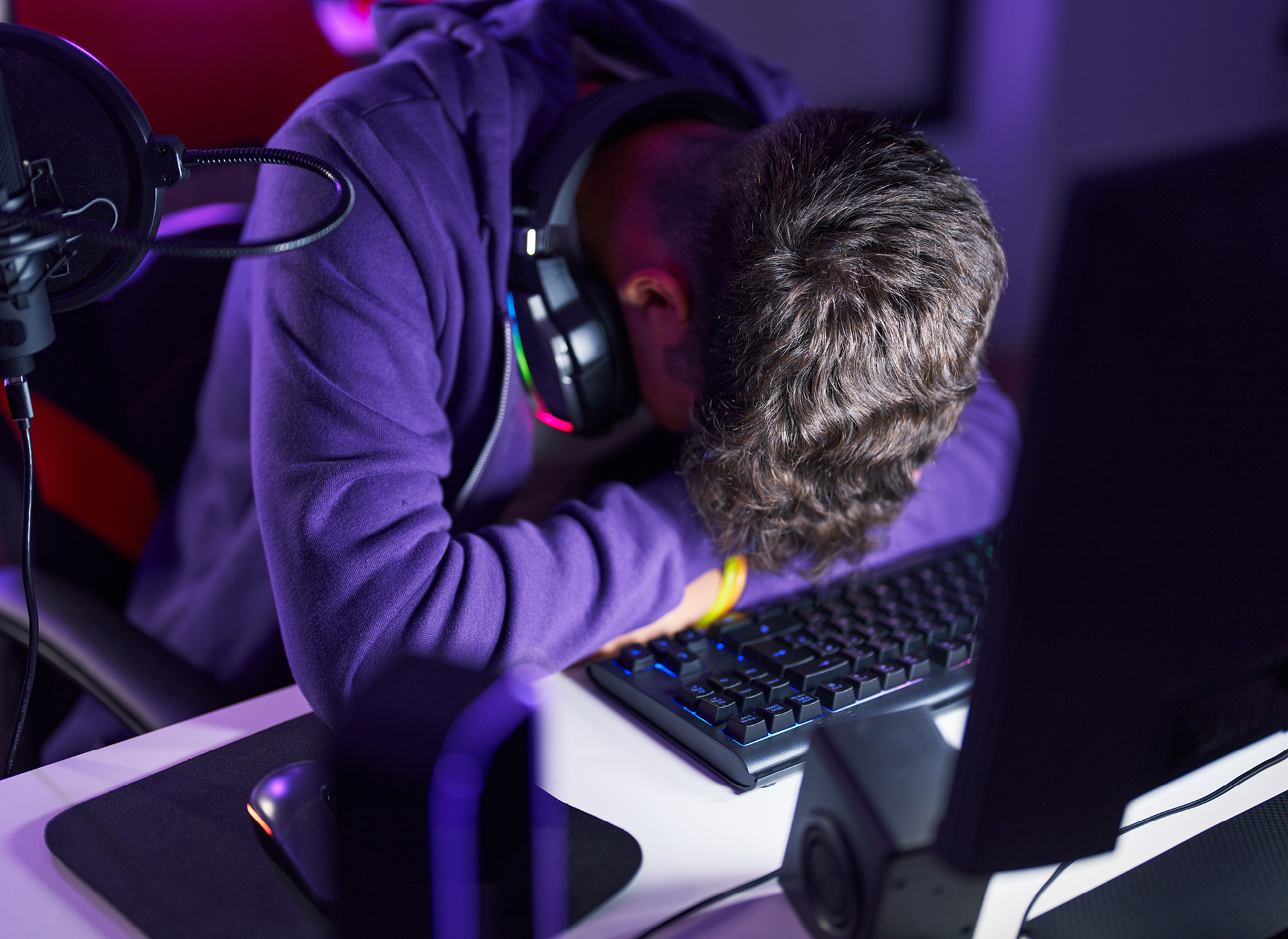 boy in blue shirt crying with hands over face and laptop on lap