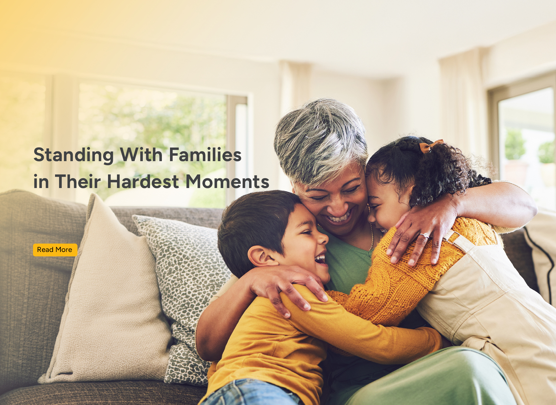 a mom sits on a sofa and hugs two small children
