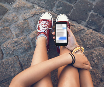 teen girl legs converse shoes bracelets and smartphone
